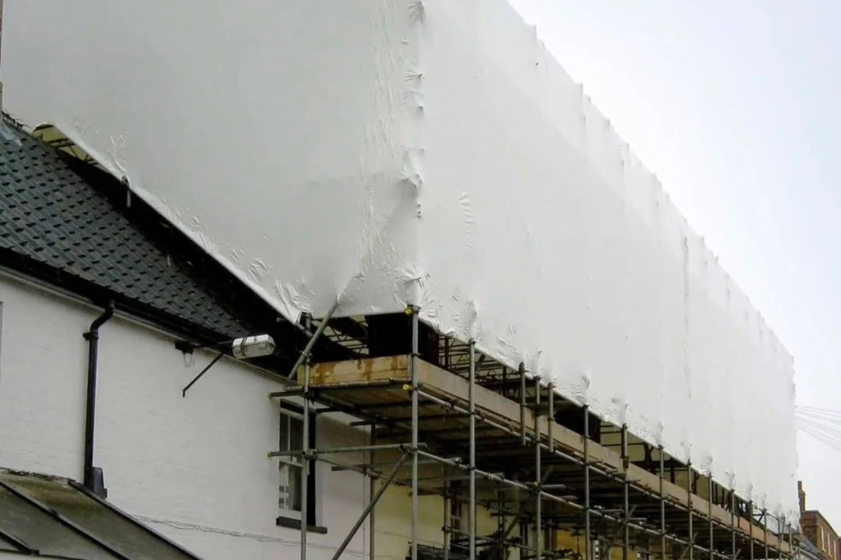 Scaffold structure covered with protective sheeting around a building
